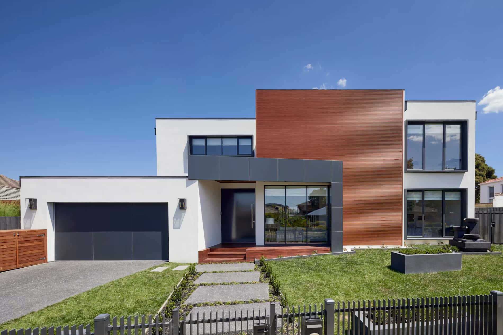 Two-story modern home with a timber-clad facade and a front lawn